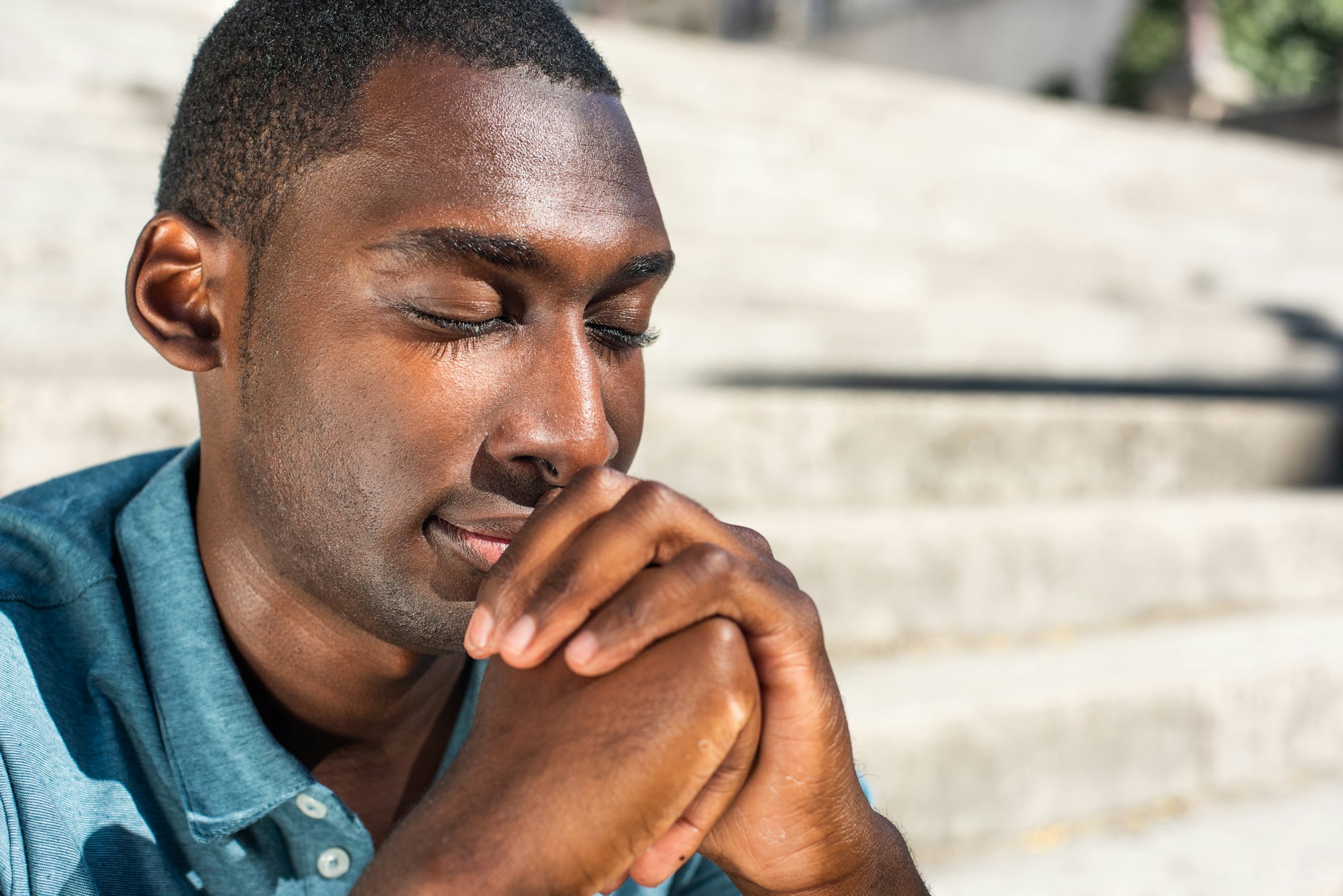 close-up-young-black-man-with-eyes-closed-praying-outside.jpg